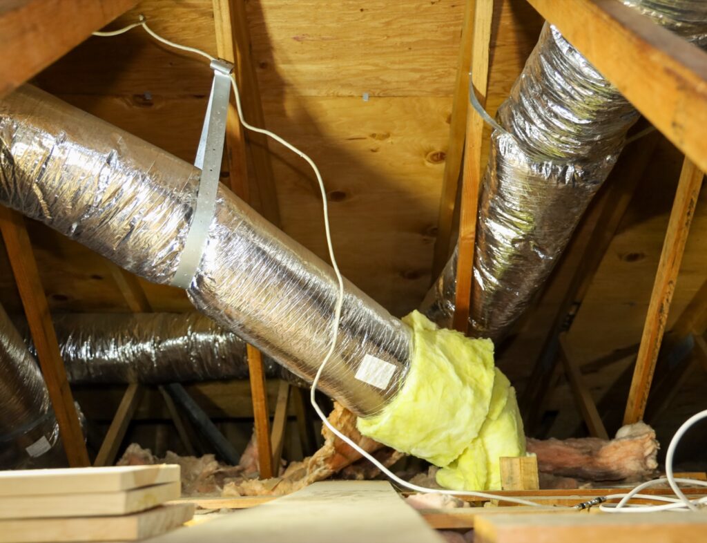 Insulated flexible HVAC ducts running between the rafters of a residential attic