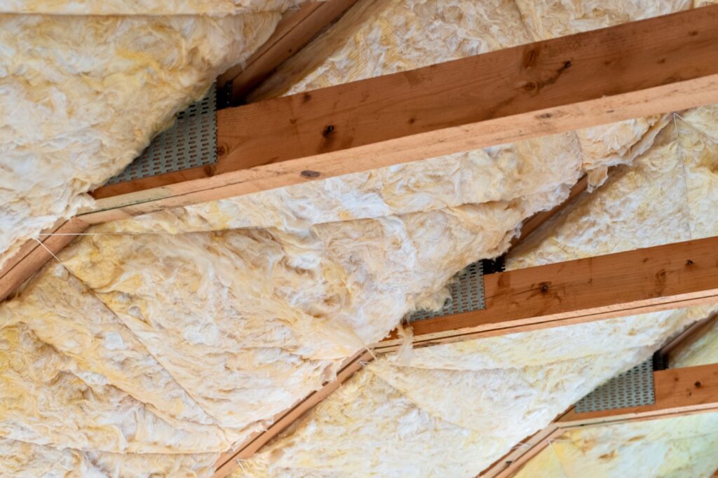 Fiberglass insulation between attic rafters with soffit ventilation baffles for airflow