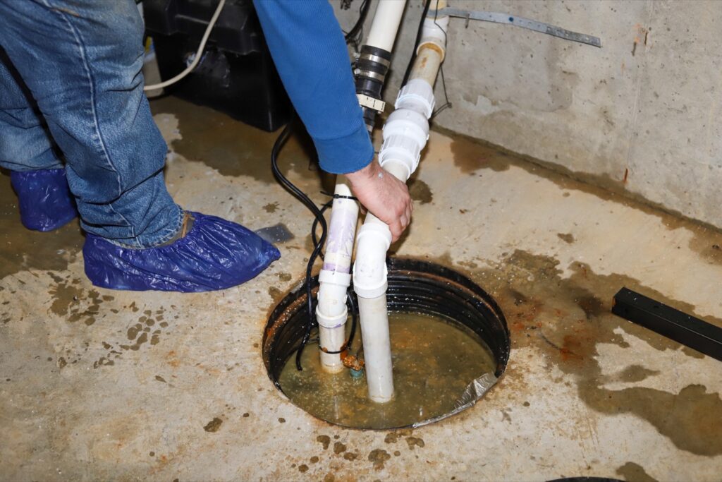 Technician servicing a sump pump set into a basement floor pit